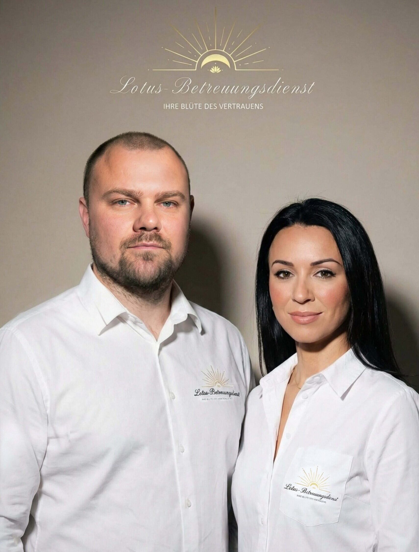 Zwei Mitarbeitende des Lotus-Betreuungsdienstes stehen nebeneinander vor neutralem Hintergrund und tragen weiße Hemden mit Logo.